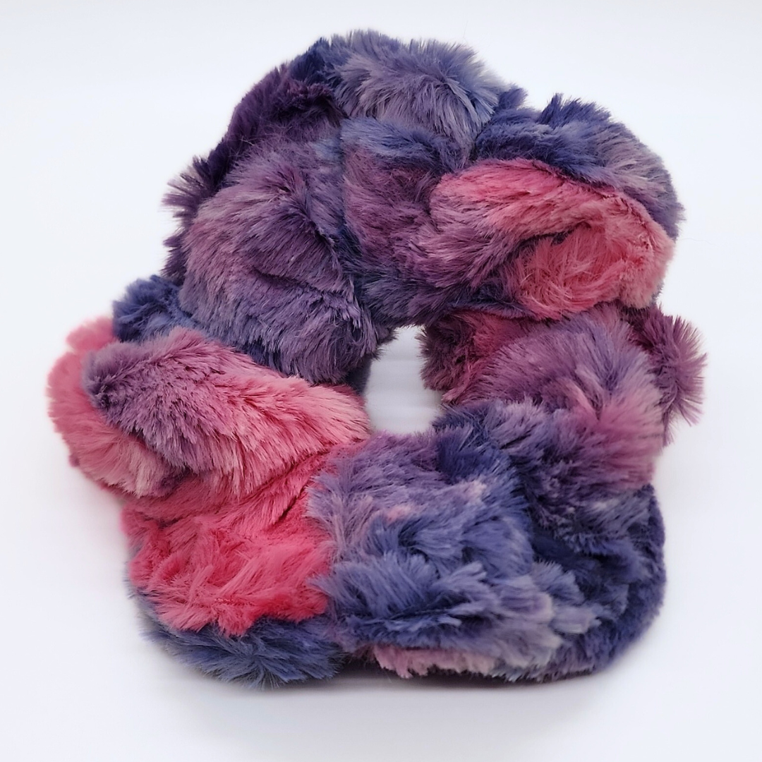 A multicolored faux fur scrunchie, with pink and purple hues, designed to look fluffy and soft.